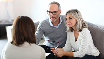 A man and woman sit on a couch discussing estate planning